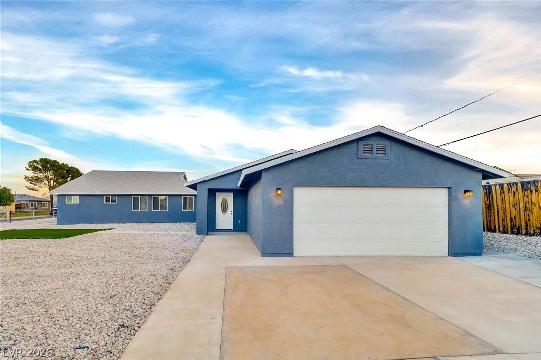 An inviting concrete driveway leads to a modern stucco home with a spacious garage.