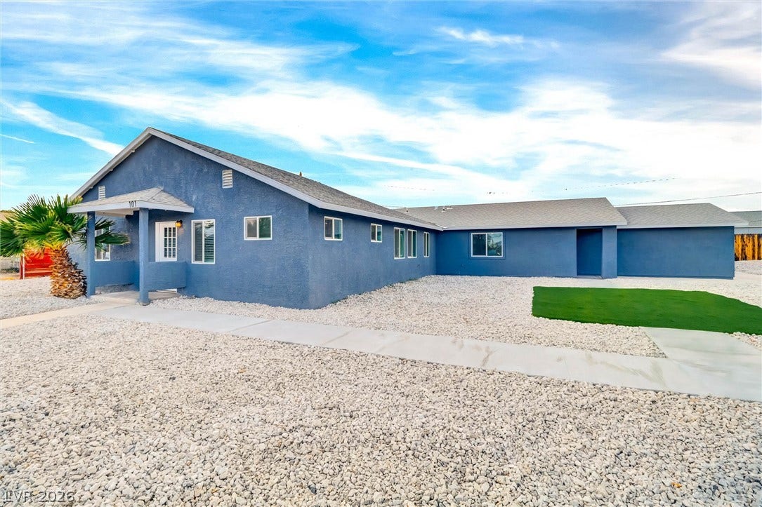 Crisp concrete walkways wind past low-maintenance gravel landscaping to a sheltered front entrance.