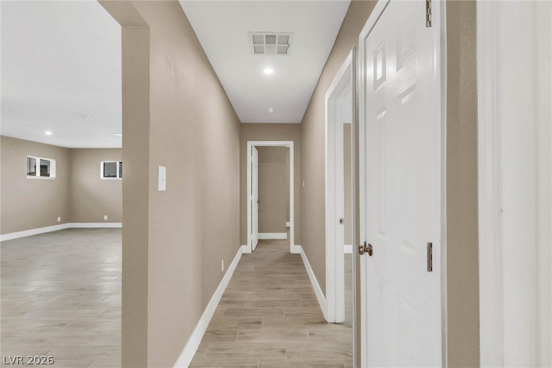 A long hallway with recessed lighting connects the main living spaces and bedrooms.