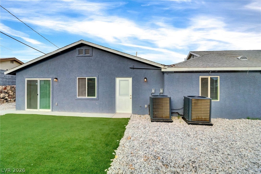 A tidy backyard area bordered by textured stucco walls under a clear sky.
