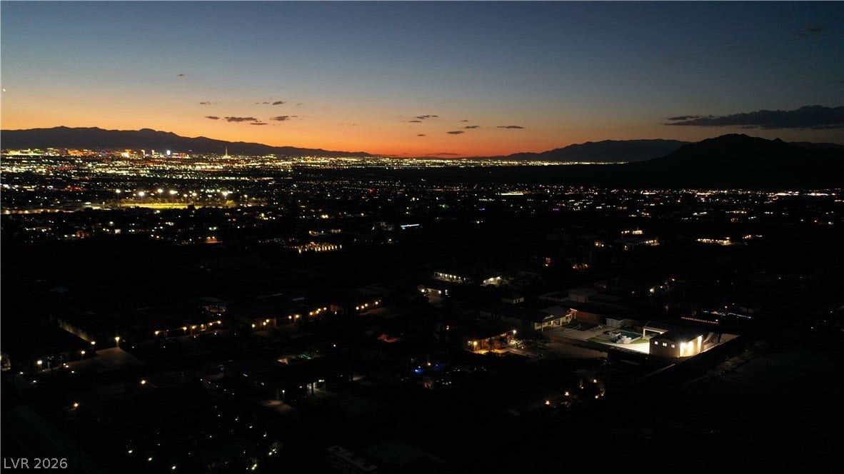 1111 E Warm Springs Road, Henderson, NV 89015 Glittering city lights stretch across the valley floor under a dramatic twilight sky.