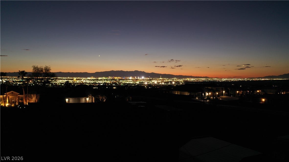 1111 E Warm Springs Road, Henderson, NV 89015 Glimmering city lights stretch across the horizon beneath a dramatic twilight sky.