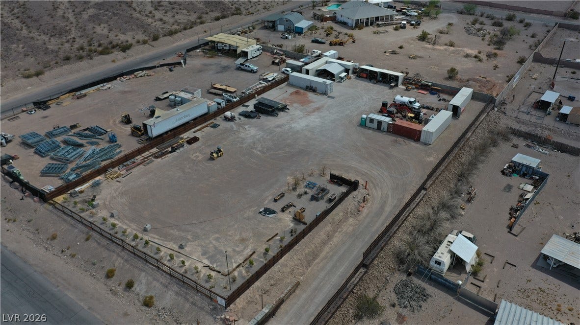 1111 E Warm Springs Road, Henderson, NV 89015 An aerial perspective showcases a spacious, fenced desert lot with multiple storage and workspace areas.