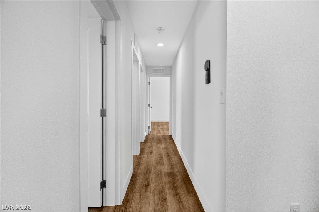 2258 Toiyabe Street, Las Vegas, NV 89156 Rich wood-inspired flooring anchors this hallway featuring clean white walls and recessed lighting.