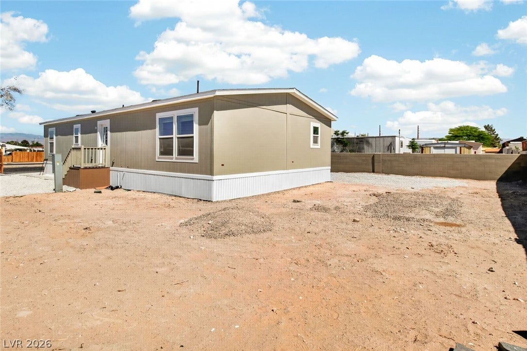 2258 Toiyabe Street, Las Vegas, NV 89156 An open dirt lot surrounds this modern manufactured home beneath a clear blue sky.