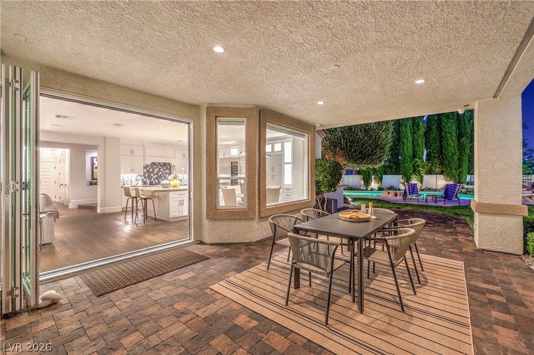 Outdoor dining with stacking doors to newly chief's kitchen, passthrough window to indoor bar and beautiful view of the saltwater pool and golf course