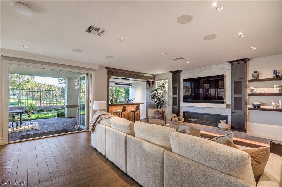 Beautifully remodeled family room featuring a 72-inch linear gas fireplace, built-in television, surround sound and custom woodwork and triple panel glass doors leads to outdoor entertaining area and golf course views