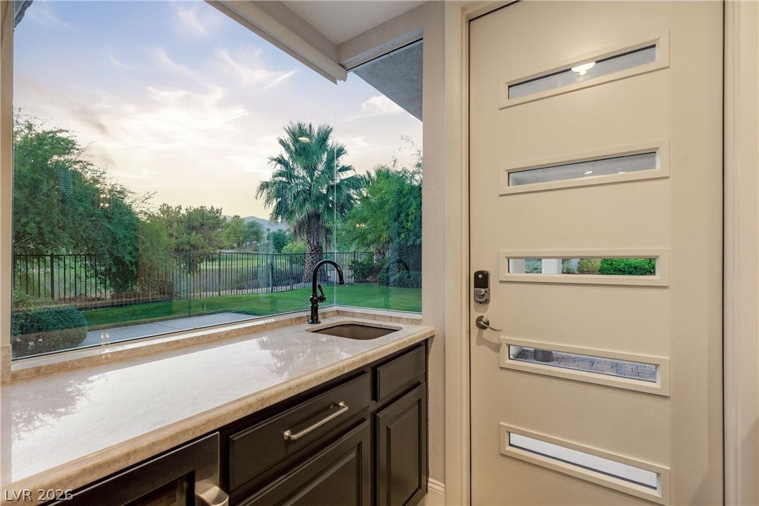 2575 Turtle Head Peak Drive, Las Vegas, NV 89135 A wet bar features stone countertops and expansive windows looking out to the yard.