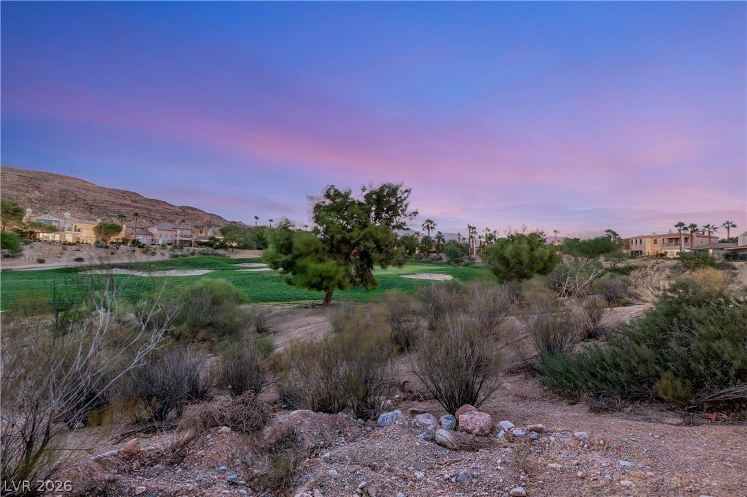 2575 Turtle Head Peak Drive, Las Vegas, NV 89135 A golf course backdrop sits beneath desert mountain views and a colorful sunset sky.