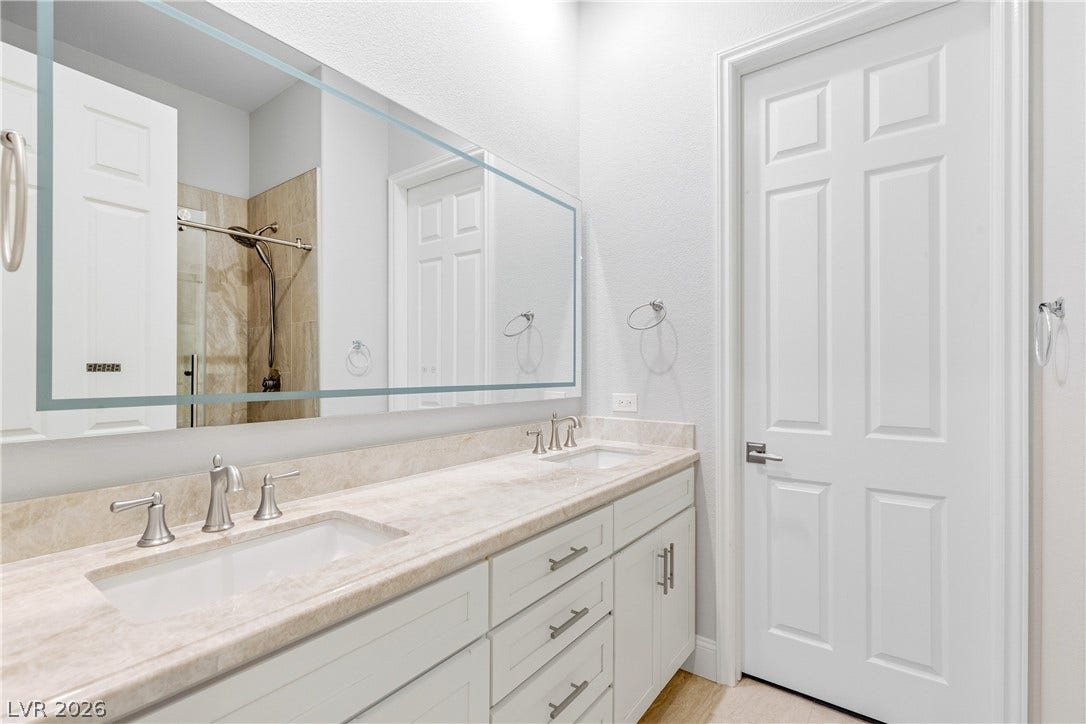 2575 Turtle Head Peak Drive, Las Vegas, NV 89135 A spacious double vanity with stone countertops highlights this contemporary bathroom design.