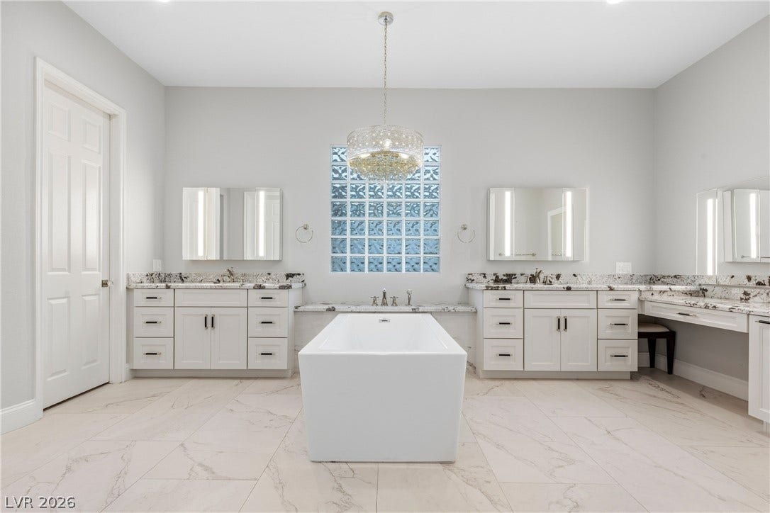 2575 Turtle Head Peak Drive, Las Vegas, NV 89135 A freestanding tub anchors this spacious bathroom featuring dual vanities and sleek tile flooring.