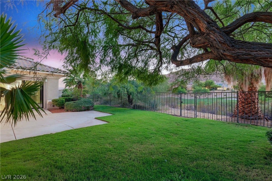 2575 Turtle Head Peak Drive, Las Vegas, NV 89135 Mature trees shade a manicured lawn framed by wrought iron fencing and scenic views.