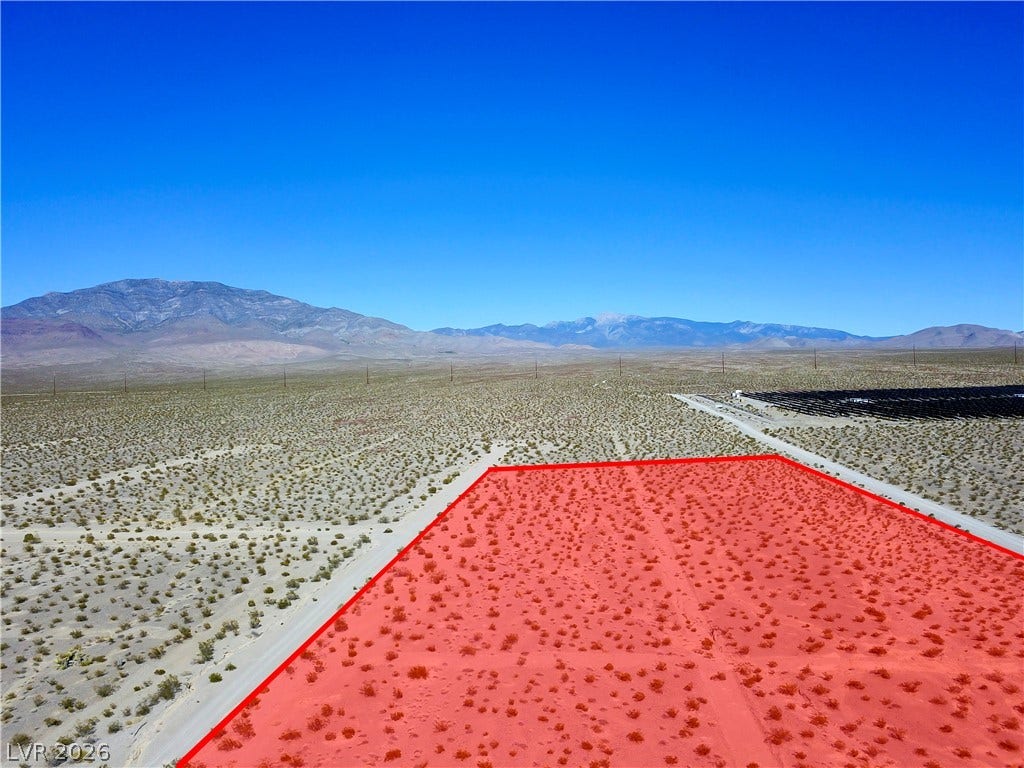 2180 E Simkins Road, Pahrump, NV 89060 Rugged mountain ridges frame this expansive desert parcel under a clear blue sky.