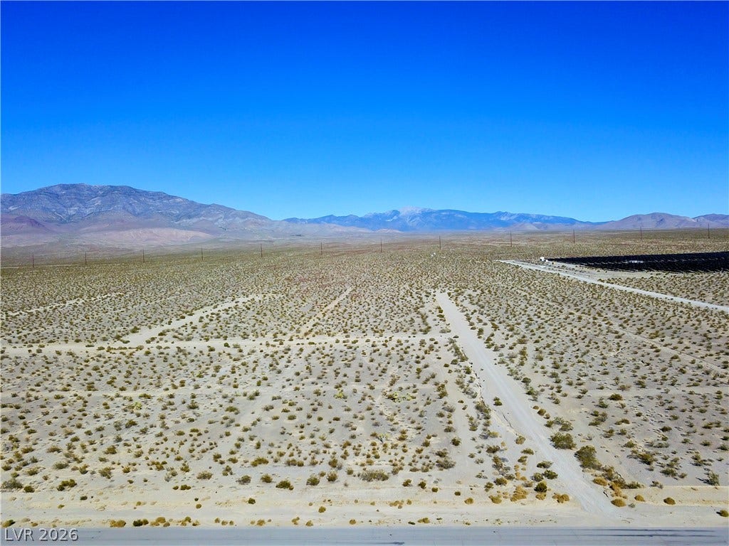 2180 E Simkins Road, Pahrump, NV 89060 Vast desert acreage framed by distant mountain ranges under clear blue skies.