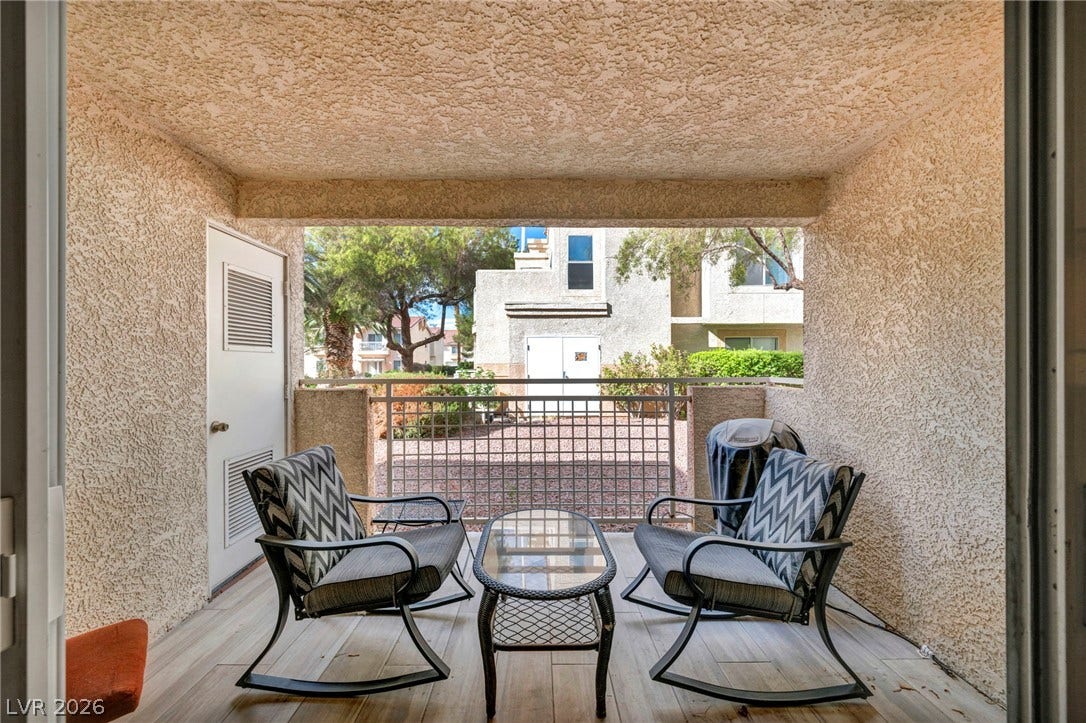 A private covered patio provides a shaded outdoor space finished with beautiful wood-look flooring, creating an cozy indoor-outdoor experience.