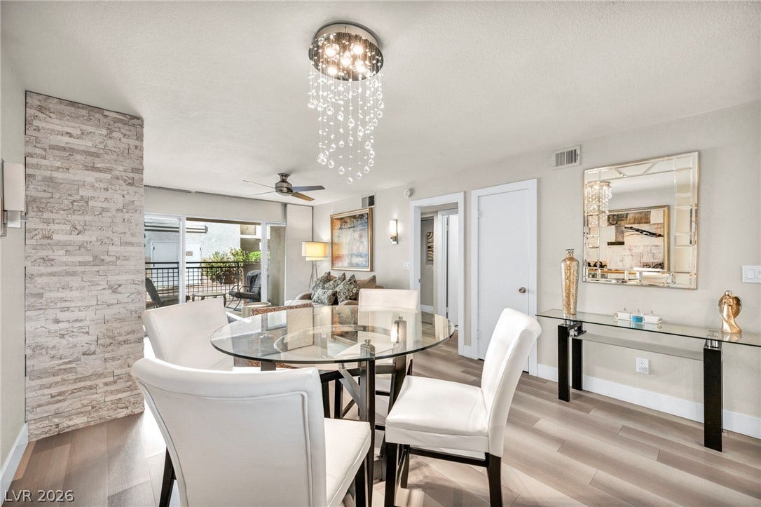 Sleek flooring, crisp white trim, and a modern stone-finished fireplace defines this dining space.