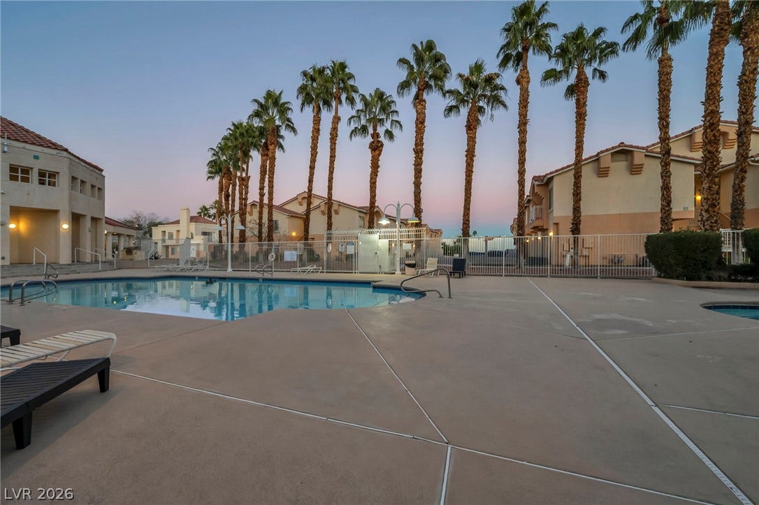 Towering palm trees frame a tranquil community swimming pool and jacuzzi.