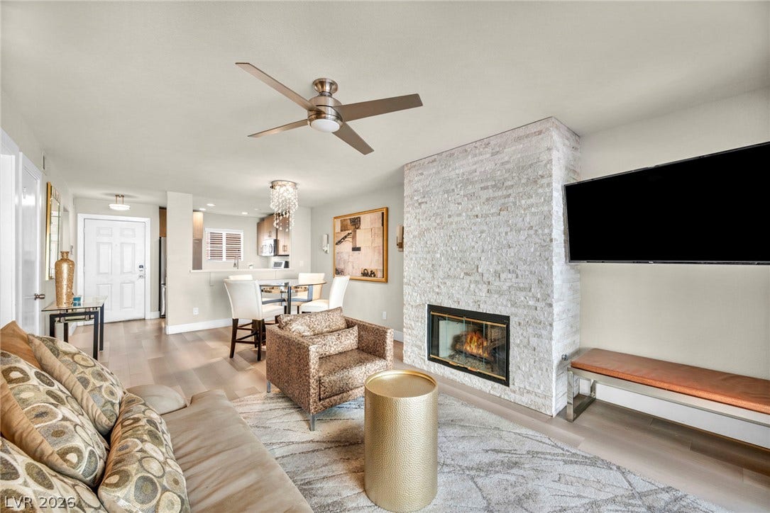 A stone fireplace adds refined warmth to this open living space with smooth wood floors.