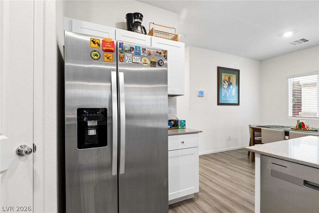 7910 Aurora Sky Street, North Las Vegas, NV 89084 Clean lines and stone counters highlight this open kitchen layout with modern wood flooring.