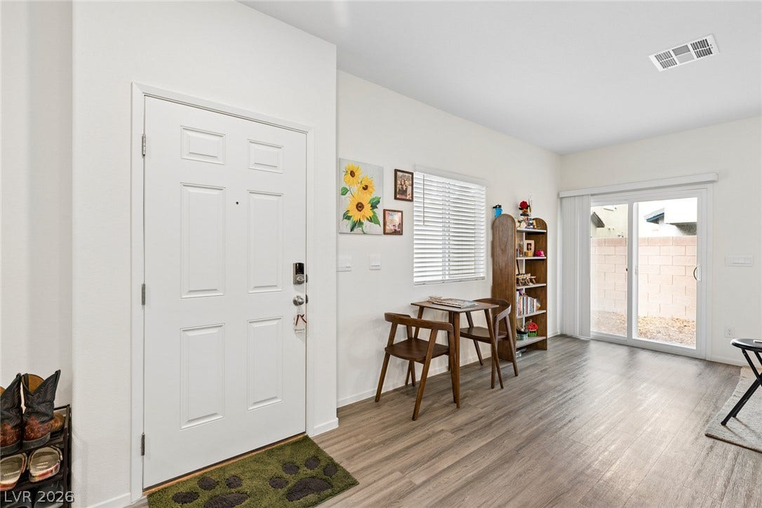 7910 Aurora Sky Street, North Las Vegas, NV 89084 A welcoming entryway transitions seamlessly into a bright living space featuring durable plank flooring.