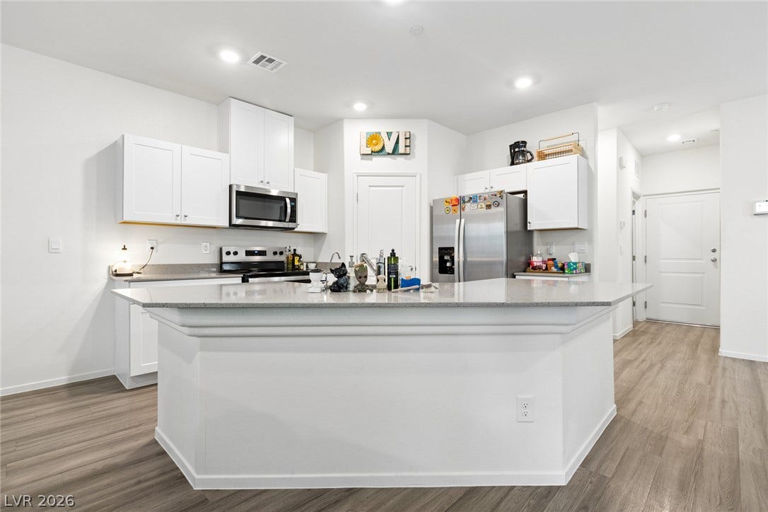 7910 Aurora Sky Street, North Las Vegas, NV 89084 Gleaming stone countertops and a spacious breakfast bar anchor this modern open kitchen design.