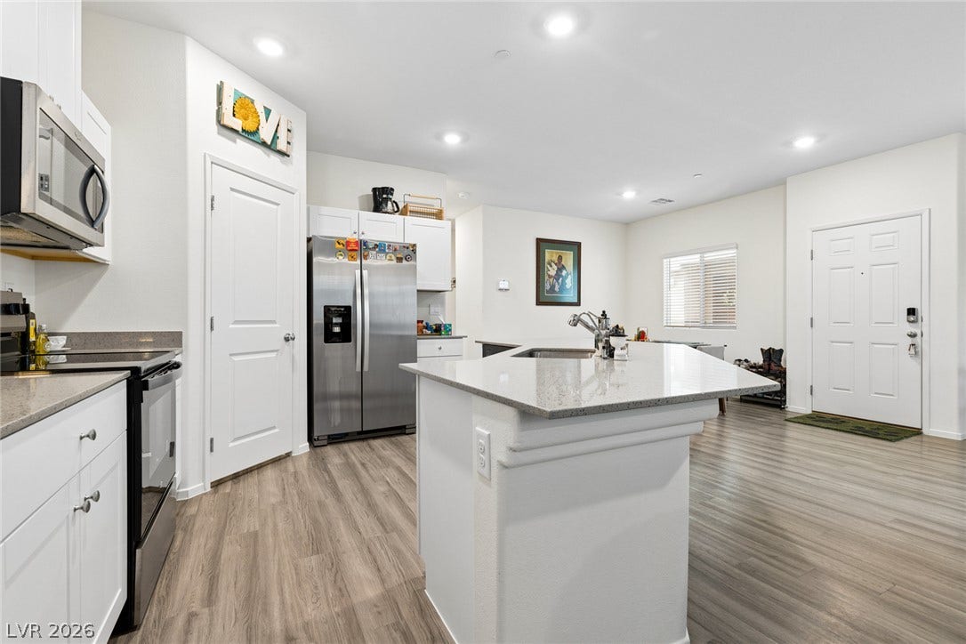 7910 Aurora Sky Street, North Las Vegas, NV 89084 Smooth stone countertops and recessed lighting elevate this modern, open-concept kitchen.