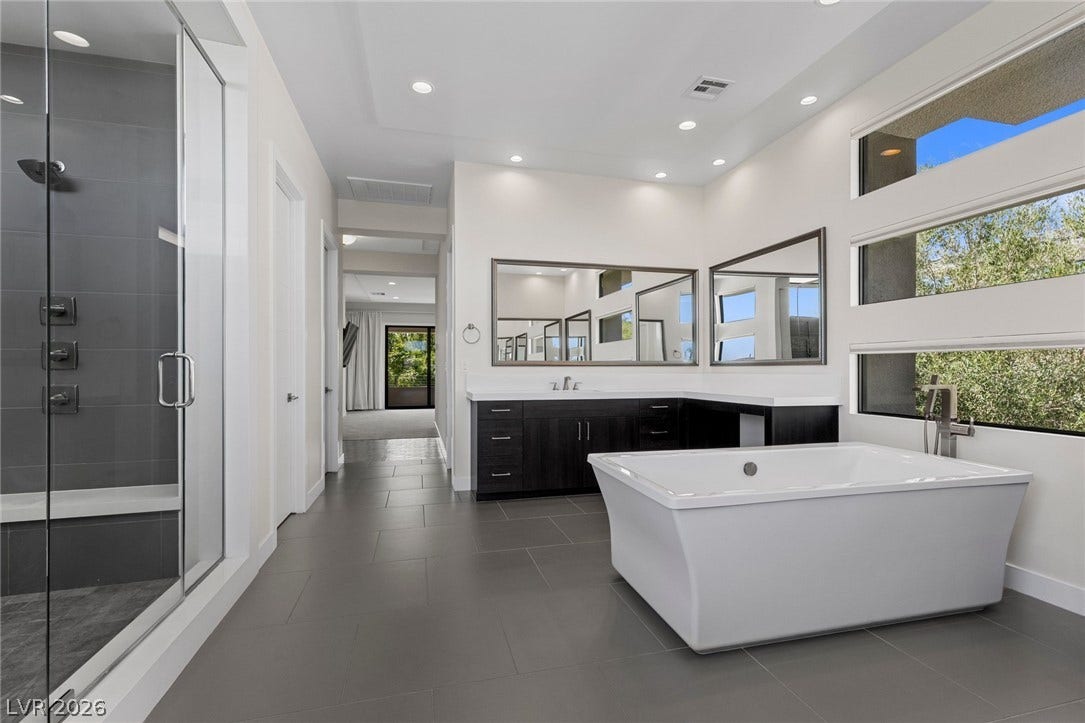 11453 Rhodolite Court, Las Vegas, NV 89135 Clean lines and large windows define this modern primary bath with a freestanding tub.