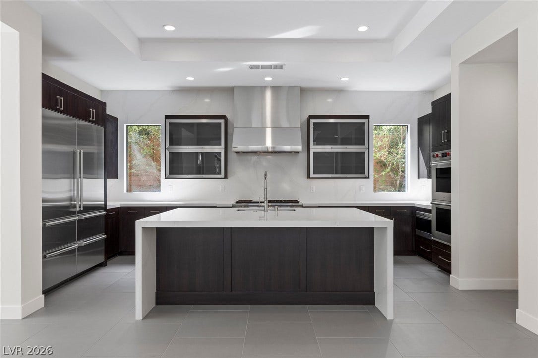 11453 Rhodolite Court, Las Vegas, NV 89135 A spacious kitchen highlighted by a waterfall island, recessed lighting, and sleek stone countertops.