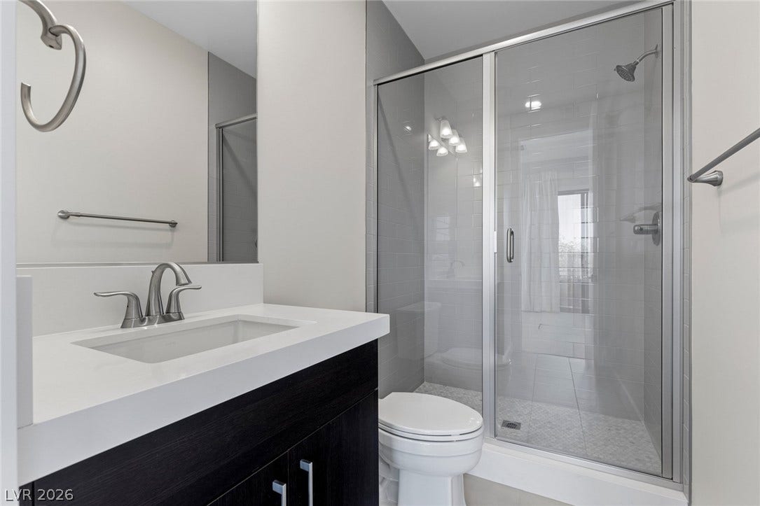 11453 Rhodolite Court, Las Vegas, NV 89135 Modern bathroom features a glass-enclosed shower alongside a sleek single vanity with stone counters.