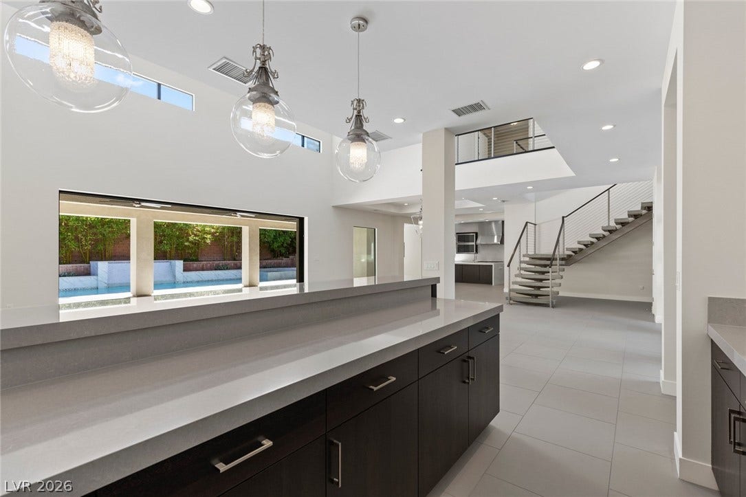 11453 Rhodolite Court, Las Vegas, NV 89135 Gleaming stone counters and soaring double-height ceilings define this modern open-concept space.