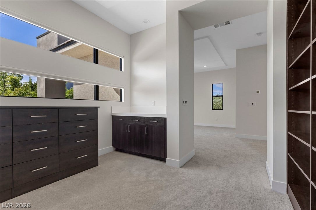 11453 Rhodolite Court, Las Vegas, NV 89135 Streamlined built-ins and custom cabinetry elevate this modern storage space with soft carpet underfoot.