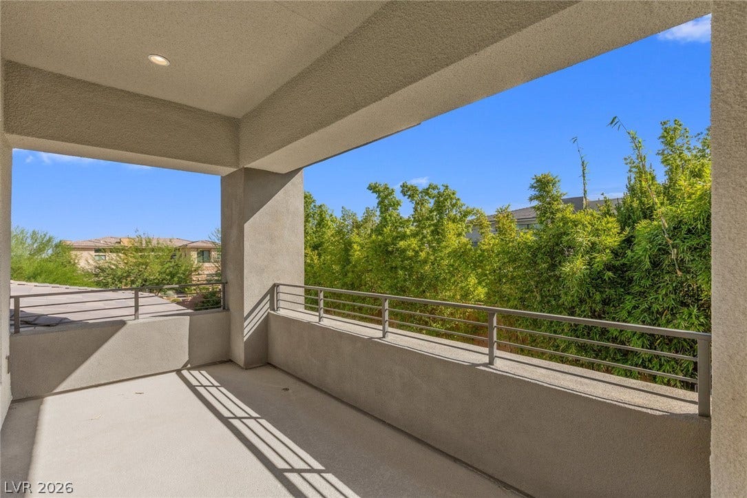 11453 Rhodolite Court, Las Vegas, NV 89135 A private covered balcony overlooks lush green trees under a clear blue sky.