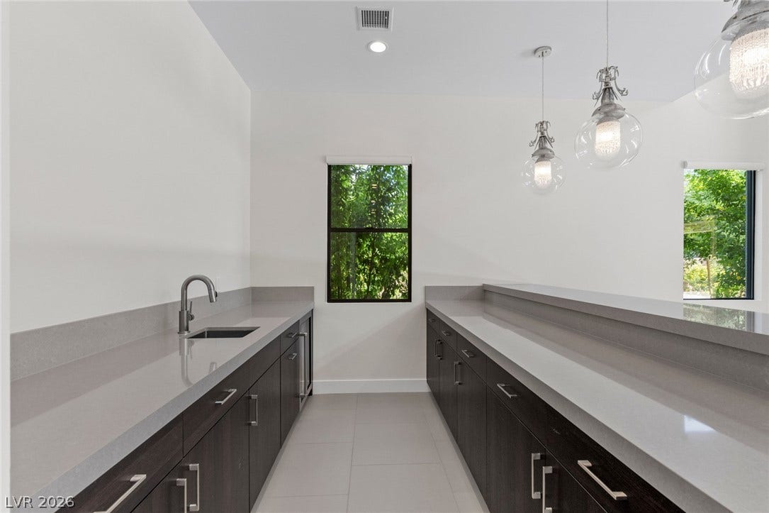 11453 Rhodolite Court, Las Vegas, NV 89135 Streamlined quartz countertops and clean modern cabinetry define this versatile bar prep space.