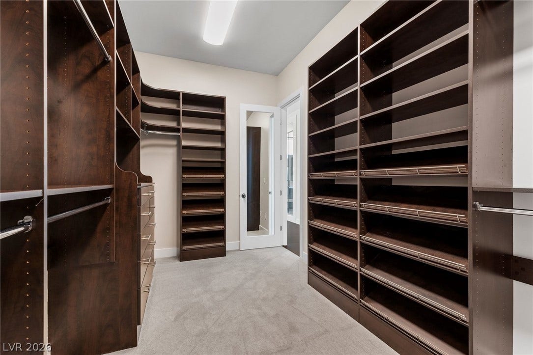 11453 Rhodolite Court, Las Vegas, NV 89135 Rich dark wood built-ins and soft carpeting define this spacious dressing area.
