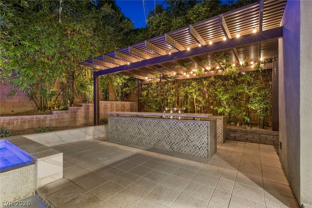 11453 Rhodolite Court, Las Vegas, NV 89135 A sleek outdoor bar sits under a structured pergola alongside a tiled patio area.