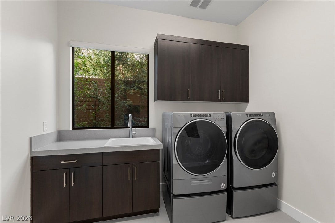 11453 Rhodolite Court, Las Vegas, NV 89135 A functional laundry space features clean countertops, built-in cabinetry, and a large window overlooking the yard.