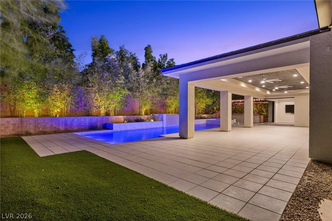 11453 Rhodolite Court, Las Vegas, NV 89135 A spacious covered patio seamlessly transitions to a sparkling pool surrounded by manicured landscaping.