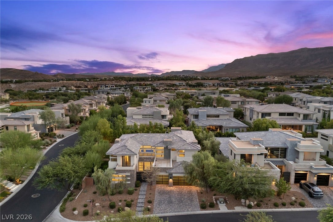 11453 Rhodolite Court, Las Vegas, NV 89135 A modern hillside neighborhood stretches toward distant mountain peaks under a twilight sky.