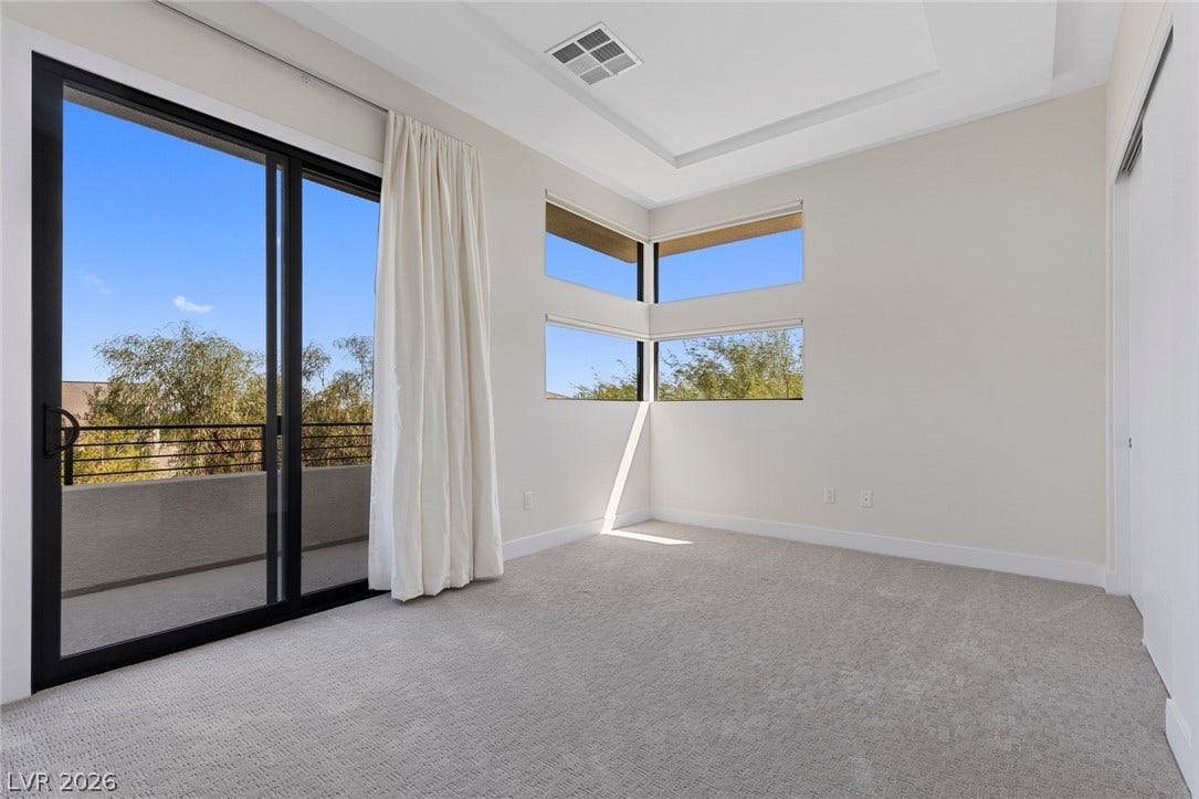 11453 Rhodolite Court, Las Vegas, NV 89135 Sliding glass doors open to a private balcony from this carpeted bedroom with tray ceilings.