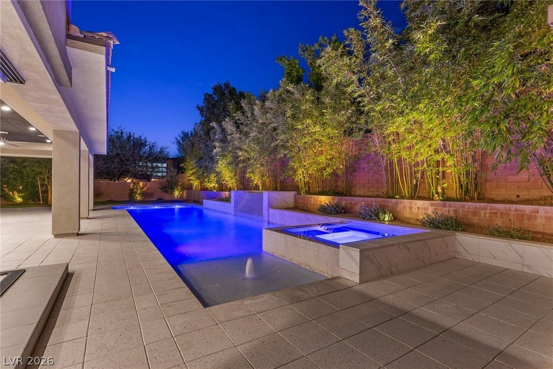 11453 Rhodolite Court, Las Vegas, NV 89135 A sparkling swimming pool and integrated spa sit bordered by tiled decking under twilight skies.