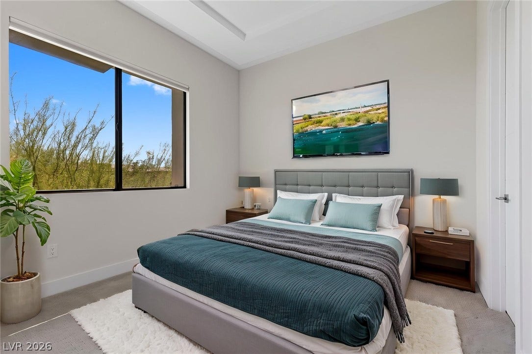 11453 Rhodolite Court, Las Vegas, NV 89135 A tall window frames desert views in this bedroom featuring a clean recessed ceiling.