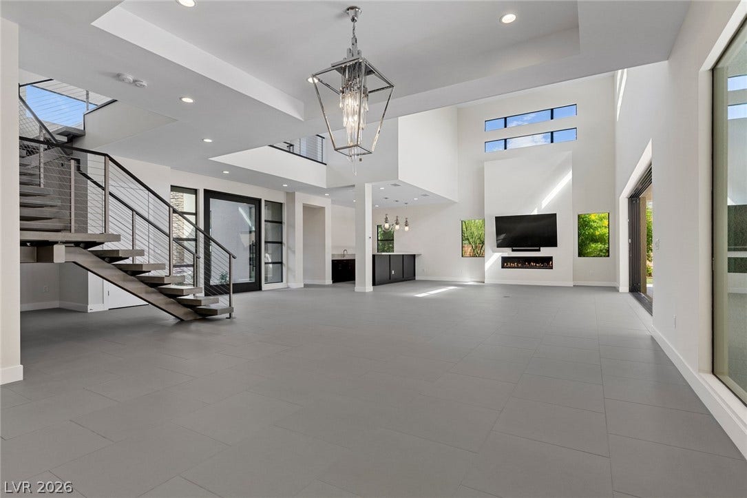 11453 Rhodolite Court, Las Vegas, NV 89135 Double-height ceilings and a sleek floating staircase define this minimalist open-concept living space.