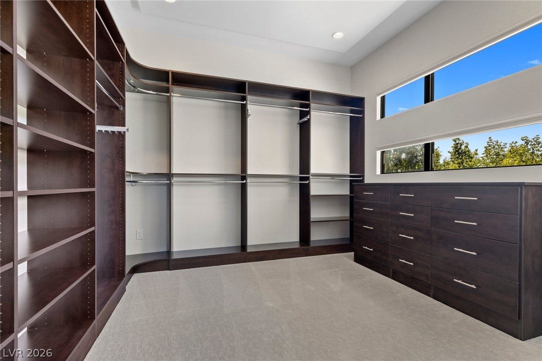 11453 Rhodolite Court, Las Vegas, NV 89135 Custom built-in cabinetry and expansive windows elevate this spacious walk-in closet.