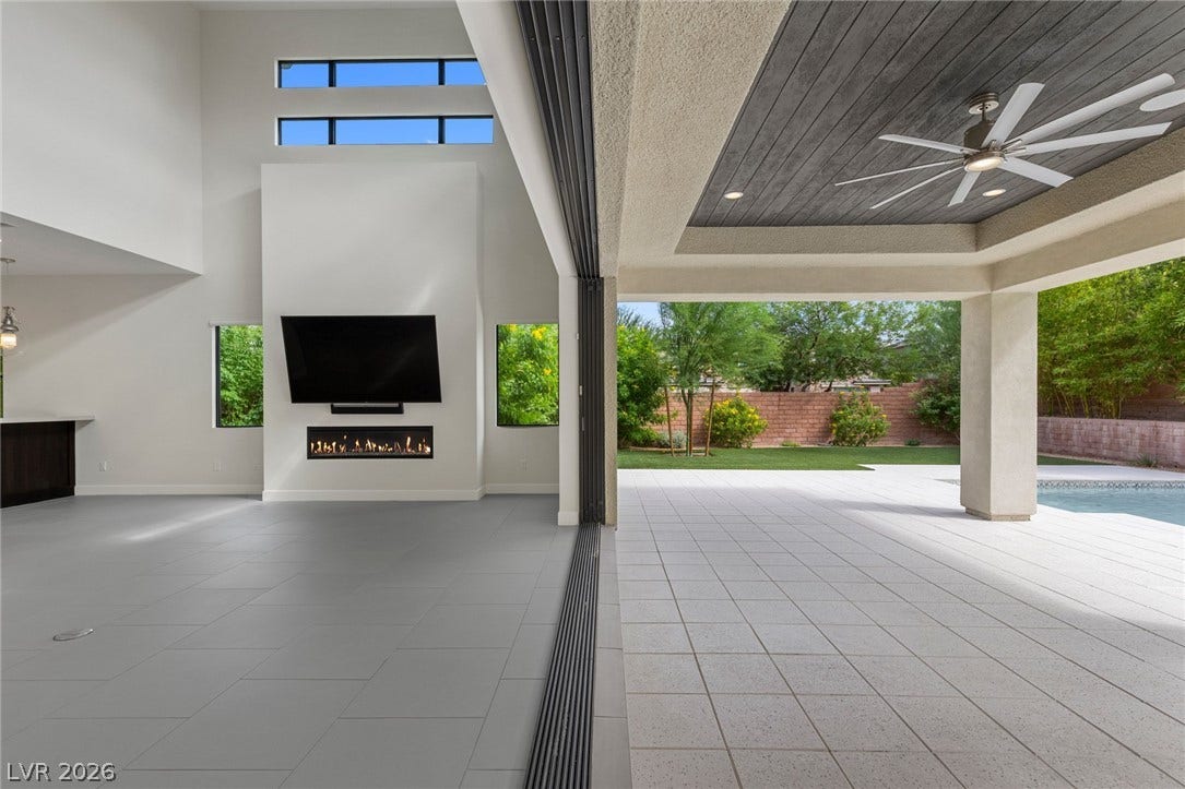 11453 Rhodolite Court, Las Vegas, NV 89135 Massive sliding glass doors connect the high-ceilinged living space to a covered patio.