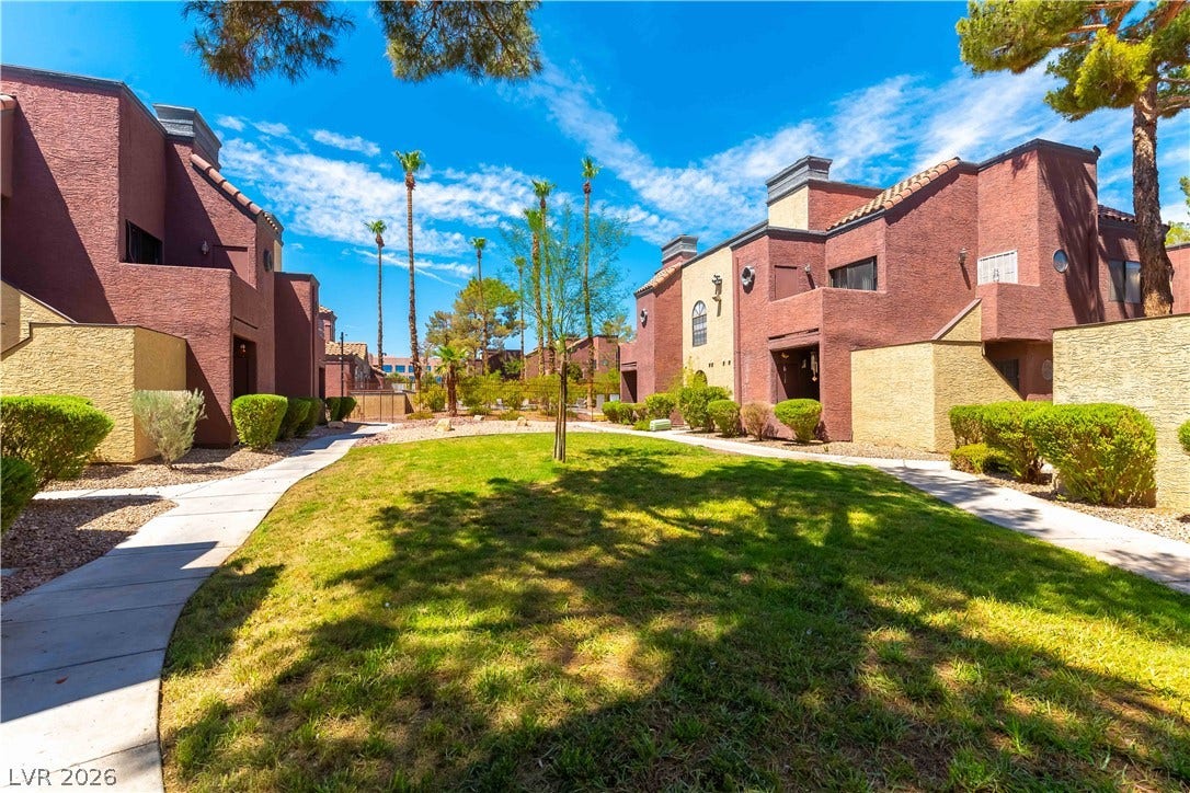 4050 Pacific Harbors Drive, #203, Las Vegas, NV 89121 Concrete walkways wind through manicured green lawns and palm trees between multi-level stucco residences.