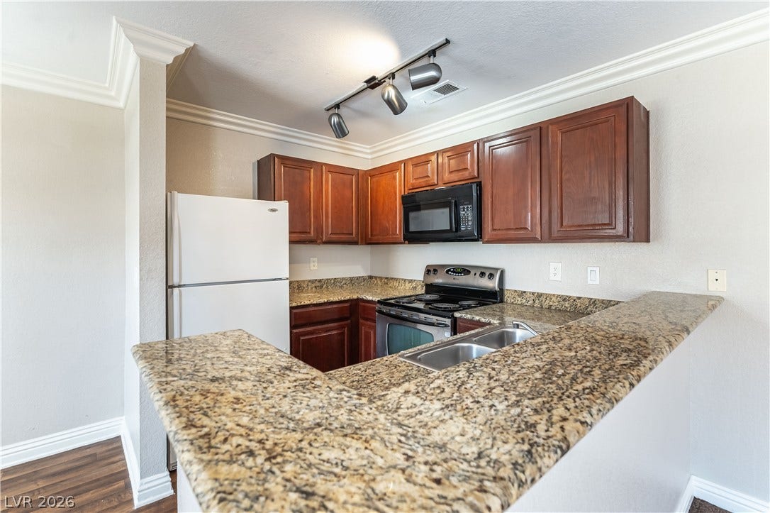 4050 Pacific Harbors Drive, #203, Las Vegas, NV 89121 Polished granite countertops wrap around this kitchen, highlighted by rich wood cabinetry and classic crown molding.