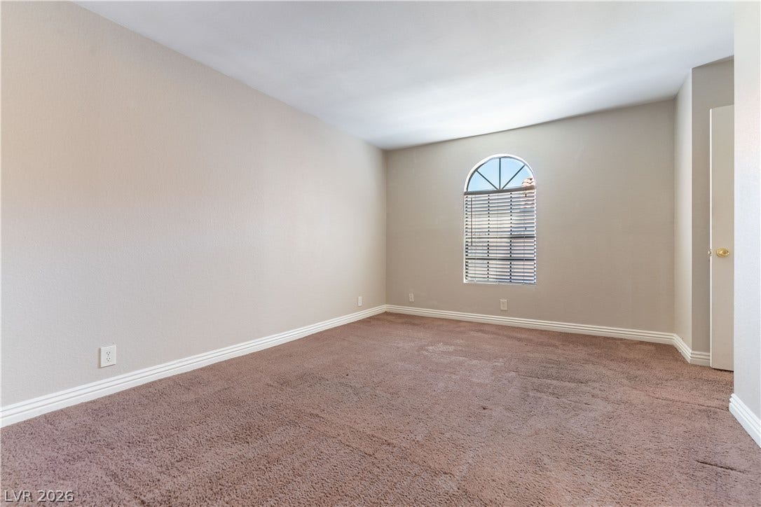 4050 Pacific Harbors Drive, #203, Las Vegas, NV 89121 Plush carpeting and an arched window define this versatile secondary bedroom space.