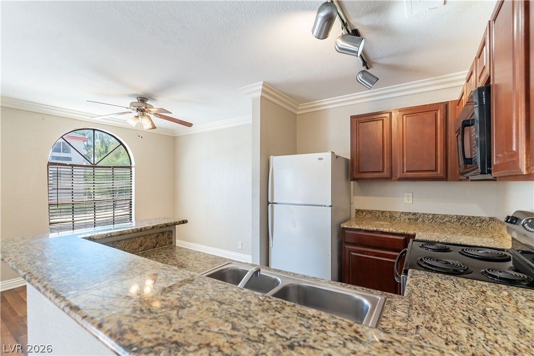 4050 Pacific Harbors Drive, #203, Las Vegas, NV 89121 Granite countertops and warm wood cabinetry define this functional cooking space.