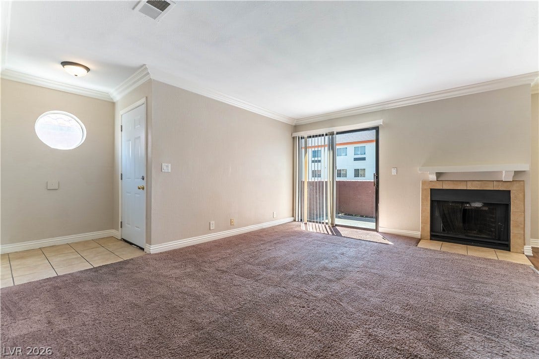 4050 Pacific Harbors Drive, #203, Las Vegas, NV 89121 Plush carpeting and a cozy fireplace anchor this open living area with sliding glass doors.
