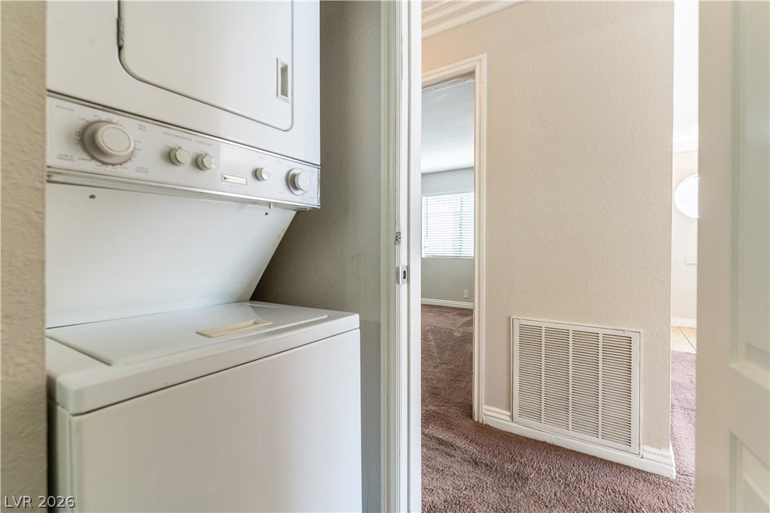 4050 Pacific Harbors Drive, #203, Las Vegas, NV 89121 An efficient laundry closet features a stacked washer and dryer unit near carpeted hallways.